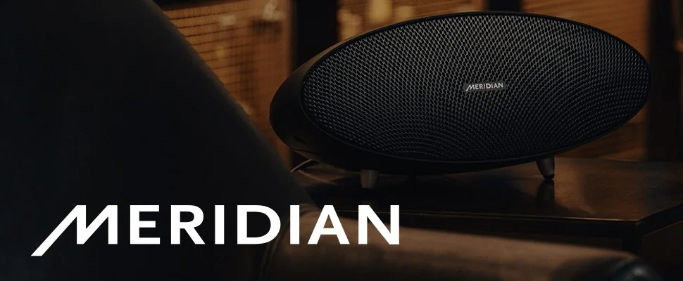 Close-up of a stylish Meridian speaker with intricate mesh design, set against a warm, softly lit background. The word 'MERIDIAN' is boldly displayed in white.