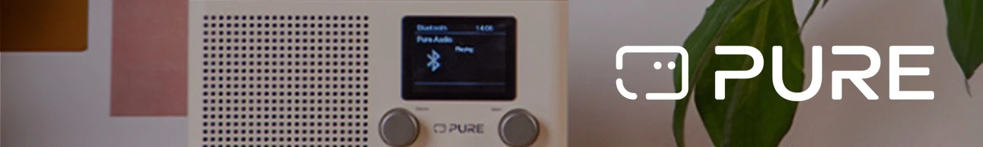 A white radio with a digital display reading "Bluetooth, Pure Audio." It features control knobs. To the right is the logo "PURE" near a plant, creating a calm vibe.