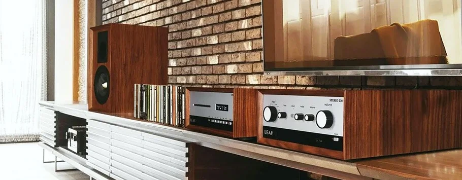 Modern living room with a retro vibe, featuring a wooden stereo system, speakers, and vinyl records on a sleek shelf against an exposed brick wall.