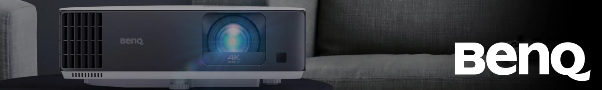 Sleek black and white BenQ 4K HDR projector on a dark surface, with a glowing blue lens. The BenQ logo is prominently displayed on the right.