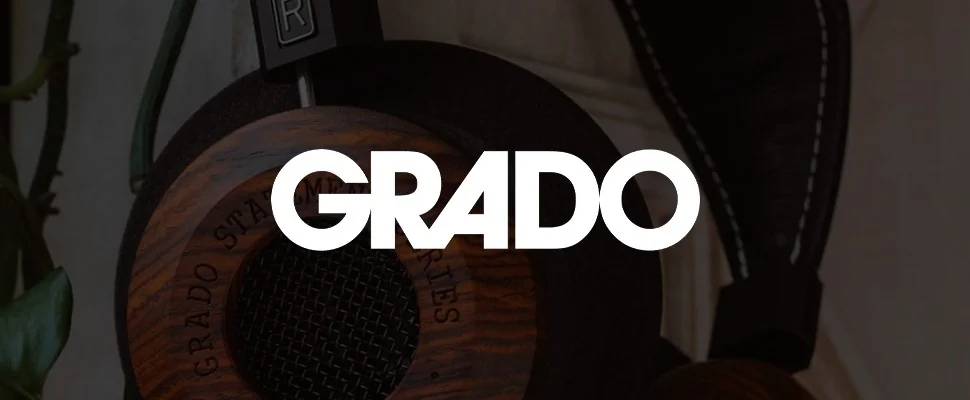 Close-up of a wooden-cased Grado headphone labeled "Statement Series," set against green leaves and a white textured background.