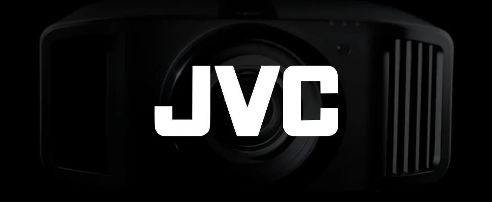 Close-up of a black camera lens on the right against a dark background. The bold white "JVC" logo appears on the left, creating a sleek, professional tone.