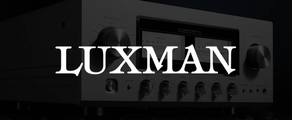 Close-up of a Luxman amplifier with two large dials and illuminated power output meters. The sleek design and dim lighting convey modern sophistication.
