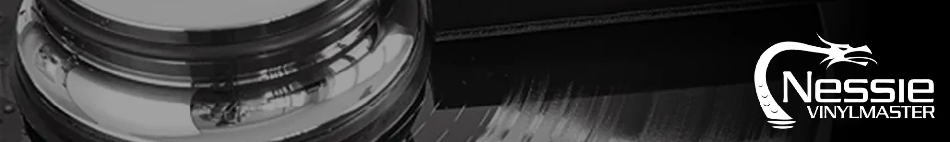 Close-up of a black and white vinyl record with a shiny metal component. "Nessie Vinylmaster" logo featuring a stylized serpent is on the right.