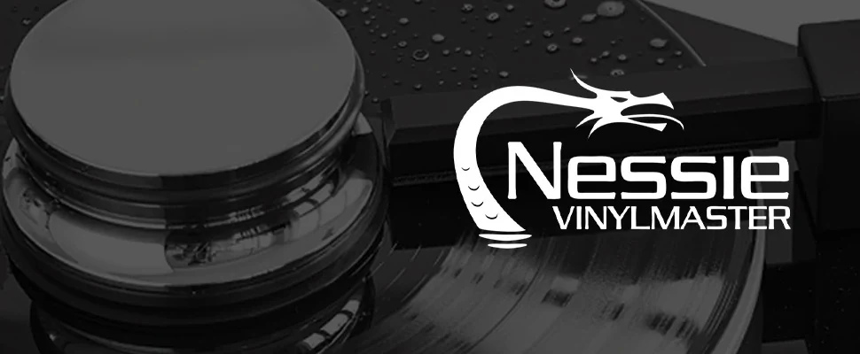 Close-up of a black and white vinyl record with a shiny metal component. "Nessie Vinylmaster" logo featuring a stylized serpent is on the right.