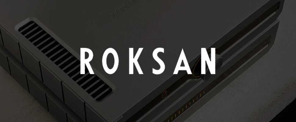 Close-up of a sleek, modern audio amplifier with a metallic surface and air vents, next to the stylized white text 'Roksan' on a grey background
