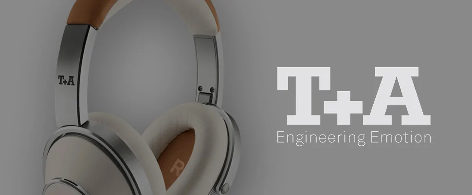 Close-up of stylish headphones with a metal finish and soft ear pads on the right; "T+A Engineering Emotion" text in white on a grey background to the left.