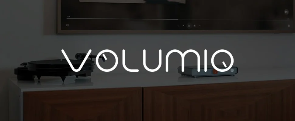 Modern audio setup with a turntable on a sleek white surface and a compact audio device beside it, resting on a wooden cabinet. The word "Volumio" is displayed.