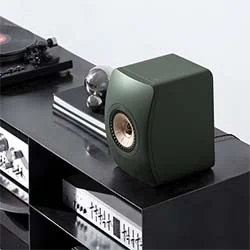 Stylish green speaker on a black shelf, next to a turntable and audio equipment, embodying modern audio design.