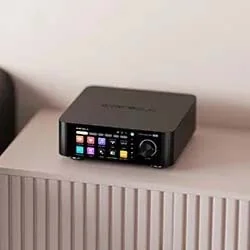 A sleek black audio device with a colourful control panel on top, placed on a textured surface, designed for modern sound management.