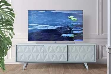 A modern television displaying Monet's water lilies sits atop a light blue, textured media console against a white wall.