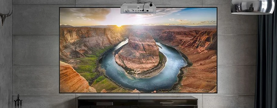 A large home theater screen displays a vivid image of Horseshoe Bend at sunset. The warm, golden light enhances the red rocks and winding river.