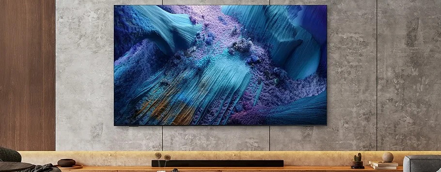 A large flat-screen TV displaying a vivid abstract image with blue and purple textures hangs on a modern concrete wall above a minimalist shelf.