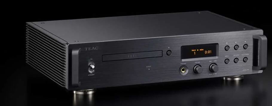 A sleek black audio CD player sits atop a wooden cabinet with a modern, minimalist design. Soft lighting casts gentle shadows.
