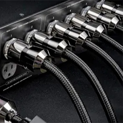 Chrome-plated power cables plugged into a black audio equipment panel, showcasing a sleek and sophisticated design with a high-tech feel.