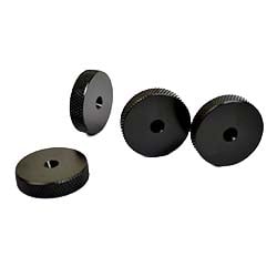 Four black knurled knobs with central holes are arranged on a plain white surface. The texture suggests a firm grip and industrial use.