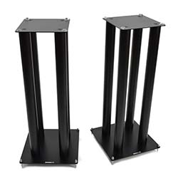 Two black speaker stands with four cylindrical legs each, featuring square bases and tops. They stand on a white background, conveying a sleek, modern look.