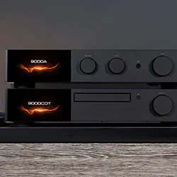 Stacked black audio equipment with glowing orange LED displays, circular control knobs, and a sleek design on a wooden surface, exudes a modern, high-tech vibe.