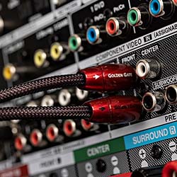 Close-up of audio-visual cables connected to a multi-colored port panel. The cables are labeled "Golden Gate" and have red connectors.