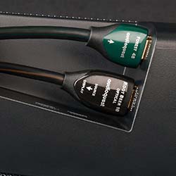 Close-up of two HDMI cables labeled "Forest 48" and "Pearl 48," plugged into a device. Cables have green and black plugs, on a dark surface.