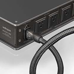 Close-up of a sleek black power strip with multiple outlets and a braided power cord, conveying a sense of modernity and functionality.