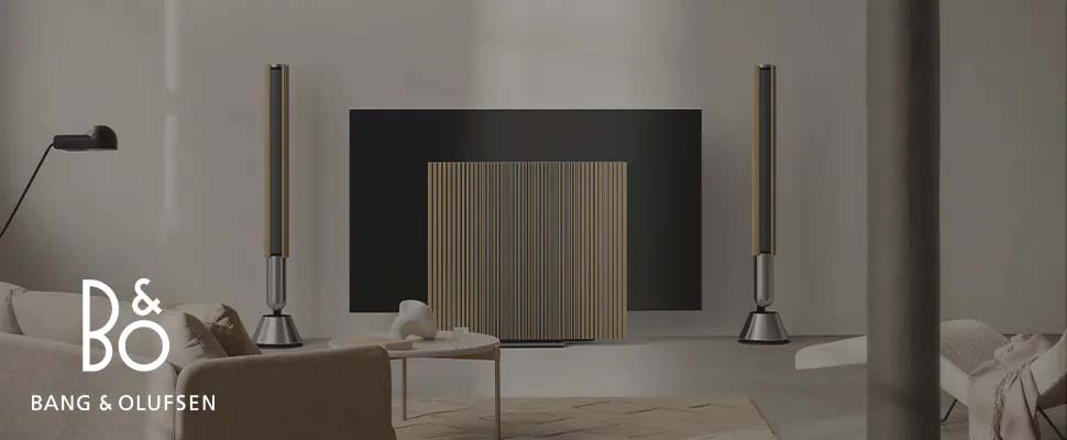 Sleek living room with Bang & Olufsen speakers flanking a minimalist TV. Neutral tones, modern decor, and a calm, sophisticated atmosphere.