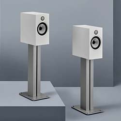 Two sleek, white speakers on modern stands against a minimalist gray background, conveying a sense of elegance and high-quality sound design.