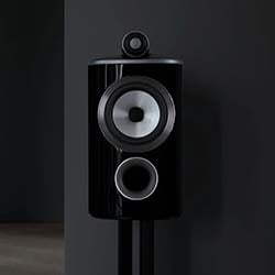 Sleek black speaker with two circular drivers on a stand against a dark background, conveying a modern, minimalist, and high-tech aesthetic.