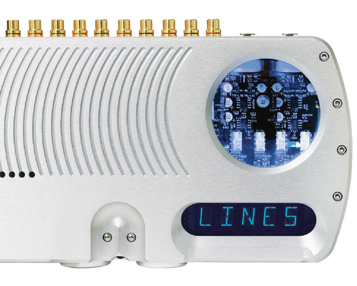 Sleek metallic device with nine gold connectors on top. Right side shows a circuit board through a circular window and a digital display reading "LINES."