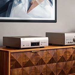 Audio equipment on a geometric wooden cabinet with a modern art piece above, conveying a sleek and sophisticated ambiance.