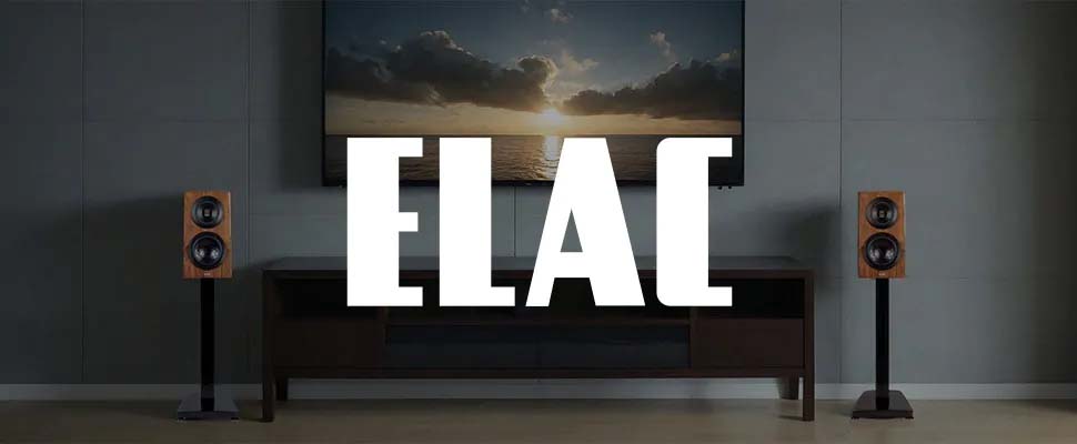 Elegant modern living room with a wall-mounted TV displaying a sunset, flanked by two sleek wooden speakers. Bold white "ELAC" text overlays the center.