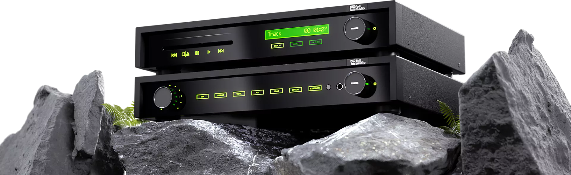 A sleek black stereo system with green LED displays is set on rugged gray rocks, creating a futuristic contrast. A few ferns add a touch of nature.