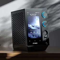 A modern black speaker with a front display shows a music track and album cover. Two blue dials on the side evoke a sleek, high-tech feel.