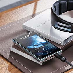 Smartphone playing music on a stack of books, with headphones nearby. The scene conveys a relaxed, modern vibe with a focus on technology and leisure.