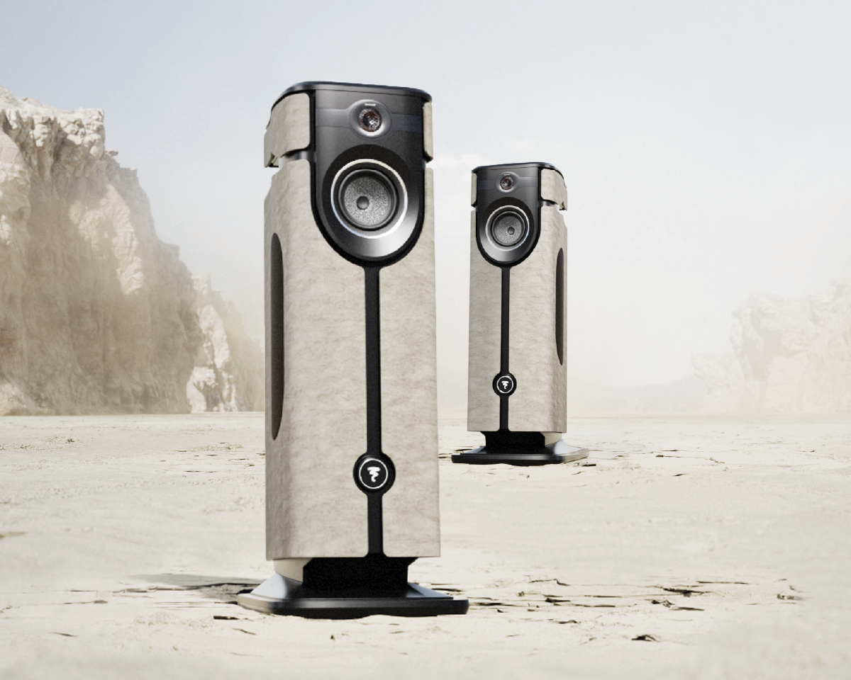 Two elegant speakers with a modern design stand on a barren, dusty landscape. The sleek, black and silver finish contrasts with the pale backdrop.