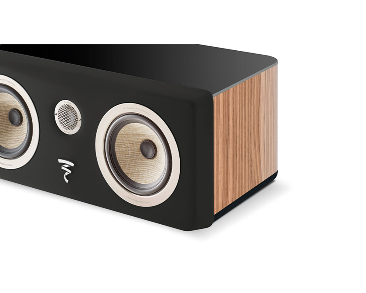 A sleek speaker with dual beige woofers and a central silver tweeter, set against a black front and wood-grain sides, conveying modern elegance.