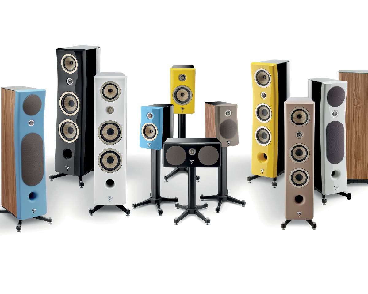 A collection of sleek, modern speakers in various colors including black, white, yellow, blue, and wood finish, arranged in a dynamic display.