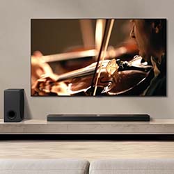 A TV on a modern stand displays a close-up of a person playing a violin, evoking a warm, immersive atmosphere. A speaker sits beside the TV.