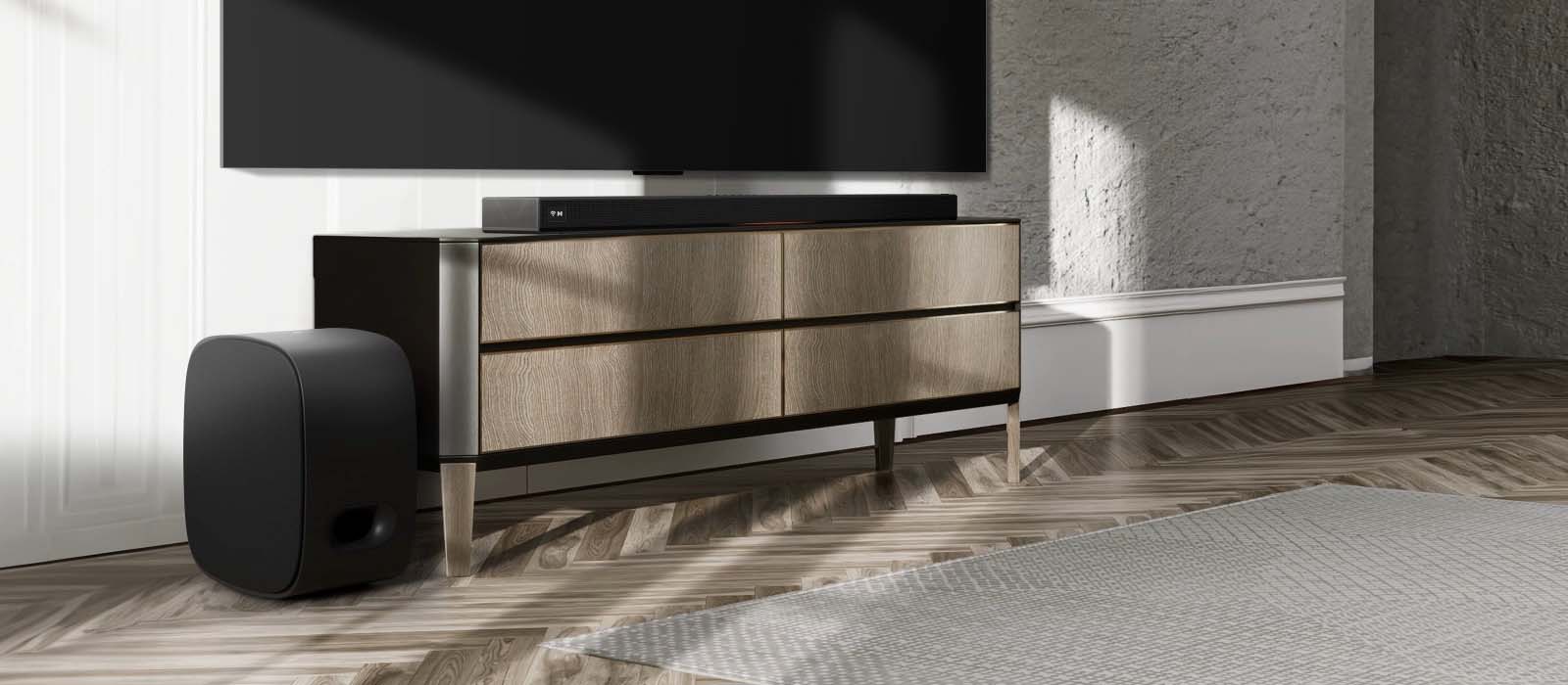 Modern living room setup with a sleek wood TV stand, large flat-screen TV, soundbar, and subwoofer. Sunlight casts shadows, enhancing the cozy atmosphere.