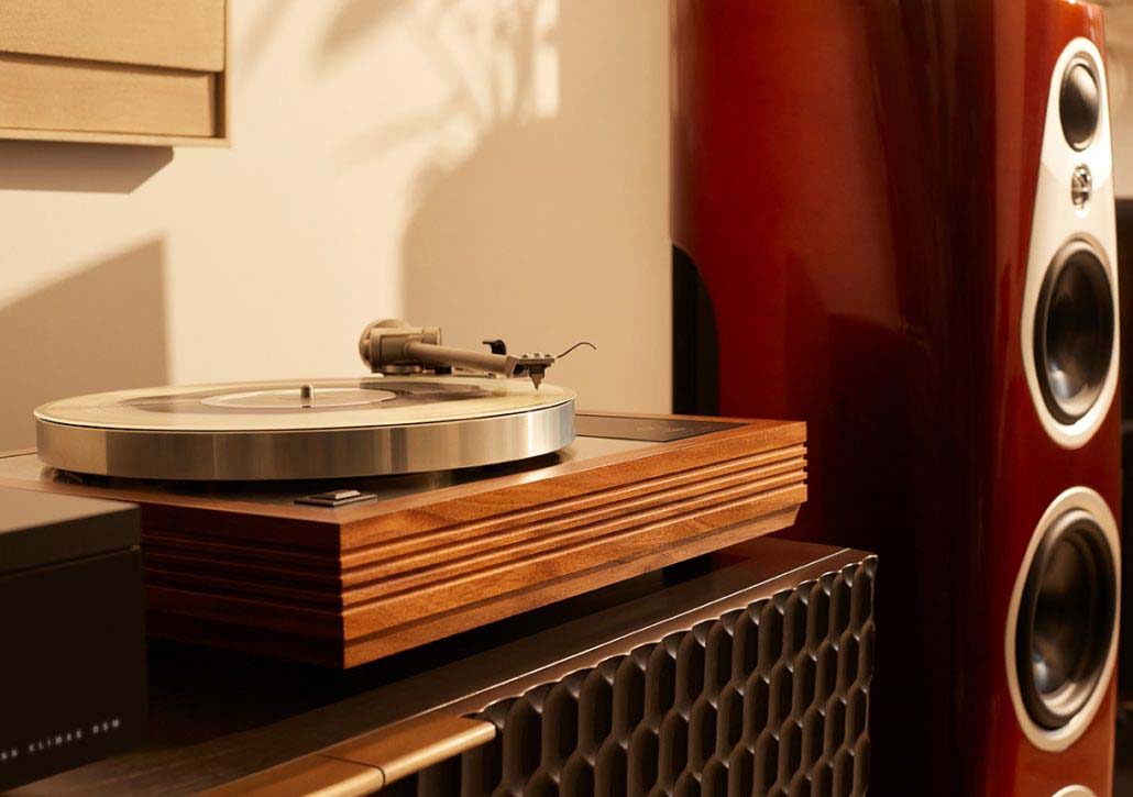 Vintage turntable with a wooden base, a vinyl record, and a needle arm, next to a sleek, tall speaker. Warm lighting creates a cozy, nostalgic ambiance.