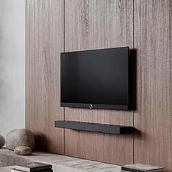 A sleek, modern TV mounted on a textured wooden wall with a black soundbar below. Minimalist decor with neutral tones and cozy ambiance.