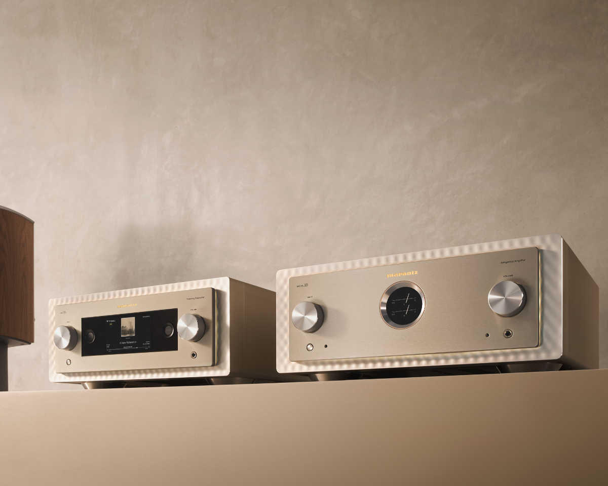 Two high-end audio amplifiers with silver knobs sit on a beige shelf. The left unit has a digital display. The setting exudes a sleek, modern feel.