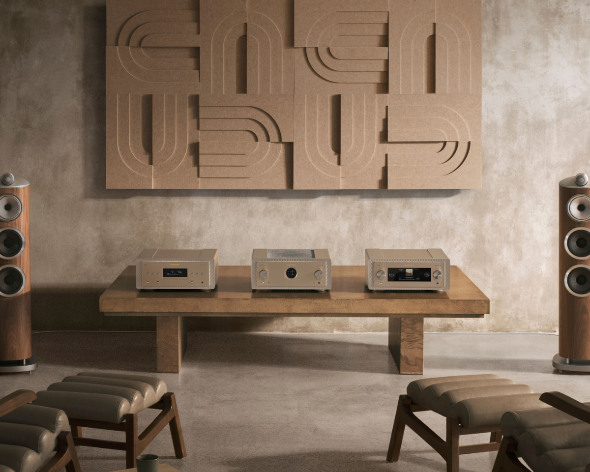 Modern audio setup with sleek amplifiers on a wooden table, surrounded by high-end speakers. Abstract wall art above creates a sophisticated ambiance.