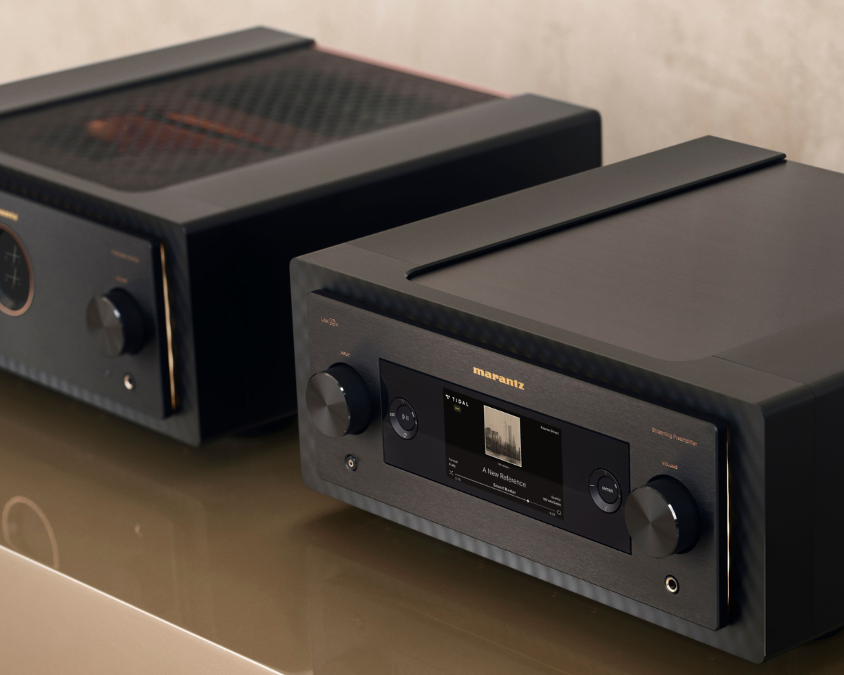 Two sleek, black audio amplifiers on a reflective surface. The front unit displays a digital interface with a music track, creating a modern, high-tech vibe.