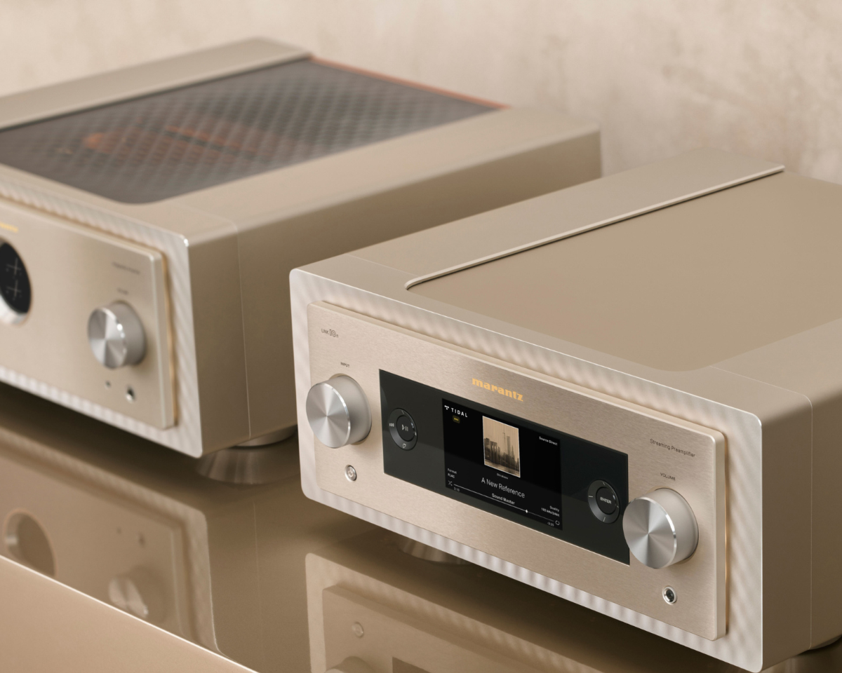 Two sleek, beige audio amplifiers with modern design. The front panel features a digital display and control knobs, set against a luxurious backdrop.