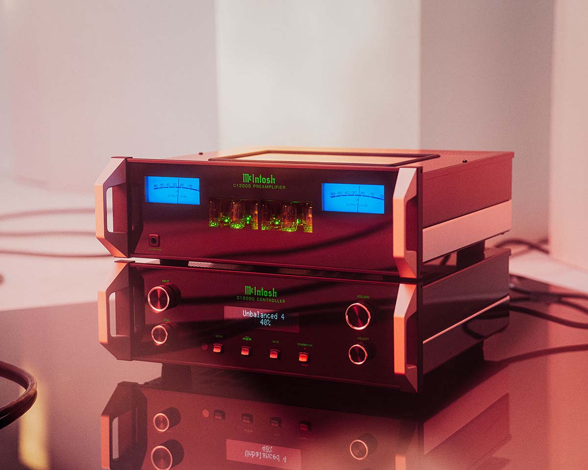 High-end McIntosh audio equipment with glowing blue meters and green-lit controls, reflecting on a sleek, shiny surface. It exudes a modern, luxurious feel.