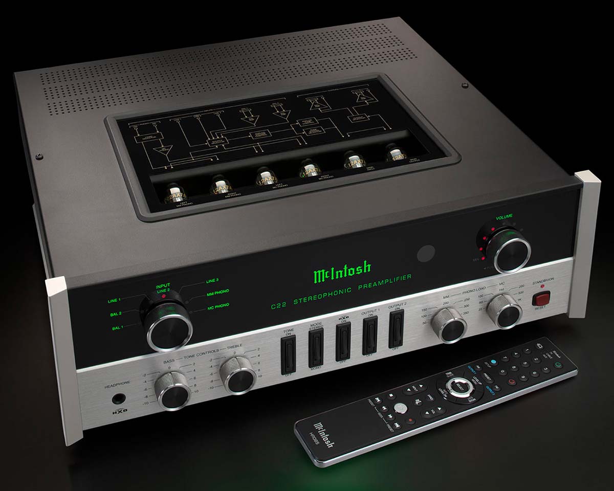 High-end McIntosh stereo preamplifier with a sleek black and silver design, glowing green display, and various control knobs. Remote control rests in front.