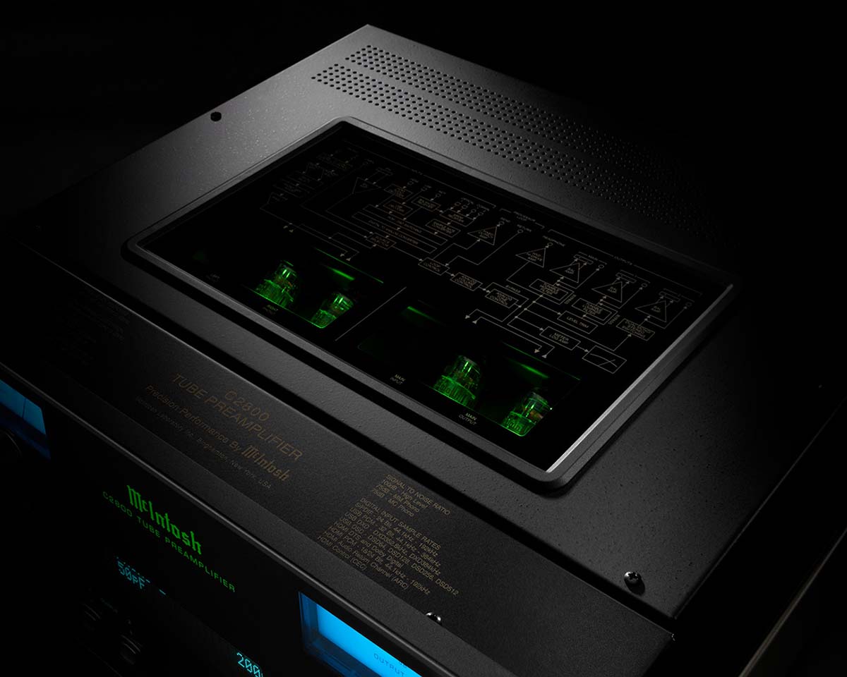 Close-up of a sleek black audio amplifier, featuring glowing green vacuum tubes visible through a transparent top panel. It exudes a high-tech, elegant vibe.