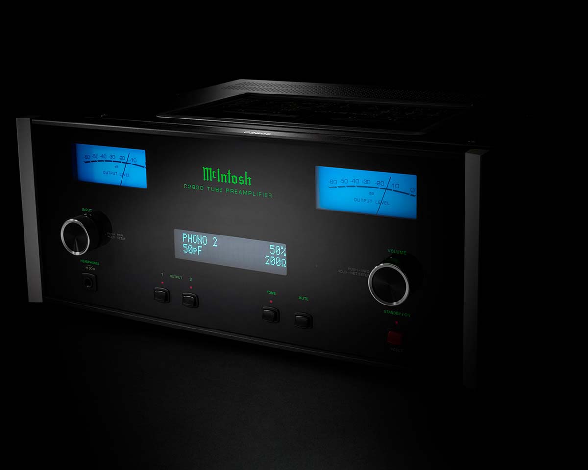 High-end McIntosh C2300 tube preamplifier in a dark setting, featuring glowing blue meters, a green logo, and sleek knobs for input and volume adjustments.
