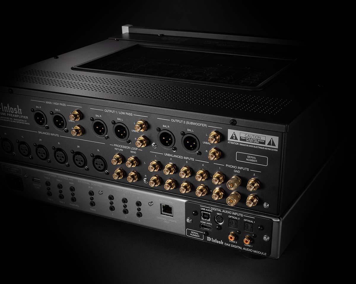 The image shows the back of a McIntosh audio amplifier, featuring numerous gold-plated input and output ports. The sleek design conveys a sense of sophistication and high-quality engineering.